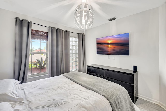 bedroom with a chandelier, visible vents, baseboards, and wood finished floors