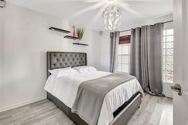 bedroom with a chandelier, baseboards, and wood finished floors