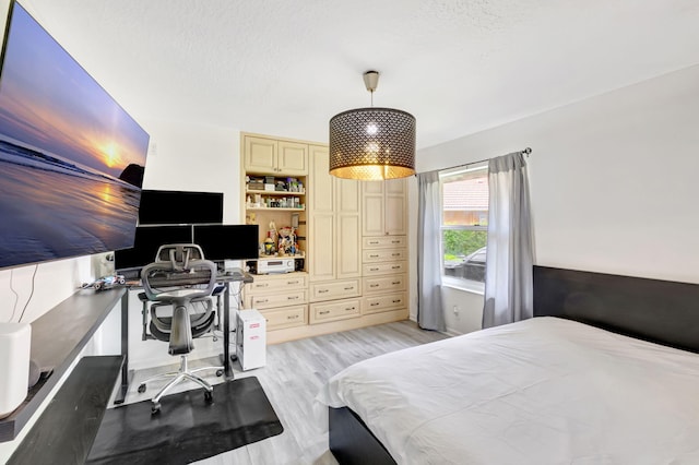 bedroom with light wood-style floors and a textured ceiling