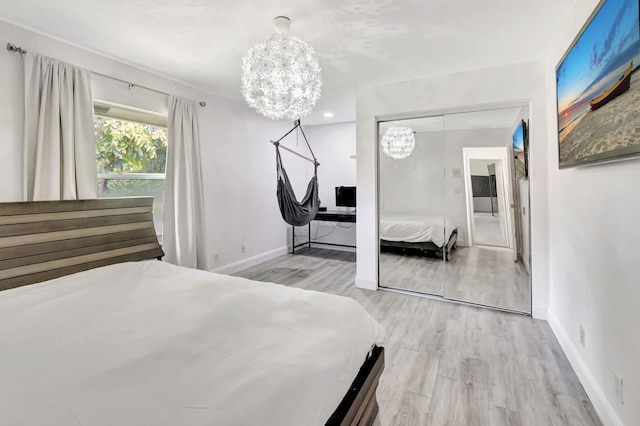 bedroom featuring a chandelier, a closet, light wood-style flooring, and baseboards