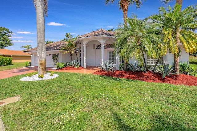 mediterranean / spanish-style home with a garage, concrete driveway, a tile roof, a front lawn, and stucco siding