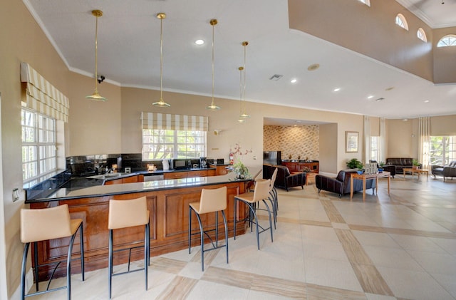 kitchen with dark countertops, ornamental molding, open floor plan, and a kitchen breakfast bar