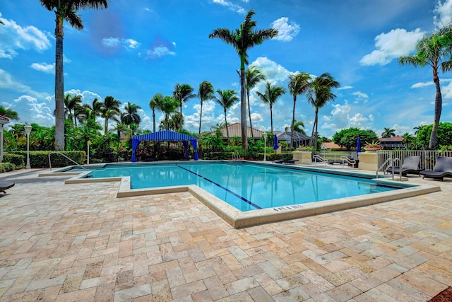 community pool with a patio and fence