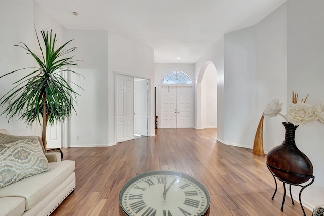 entryway featuring baseboards, arched walkways, and wood finished floors