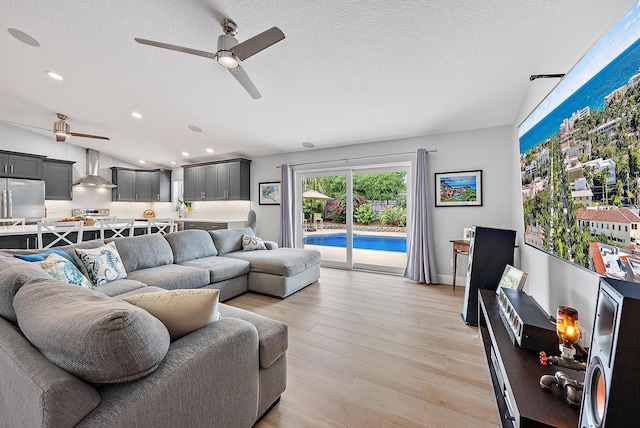 living area featuring lofted ceiling, light wood-style floors, a textured ceiling, and recessed lighting