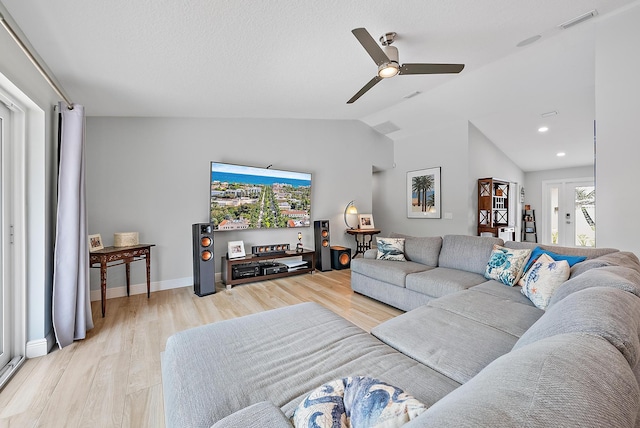 living area featuring lofted ceiling, light wood-type flooring, visible vents, and a ceiling fan