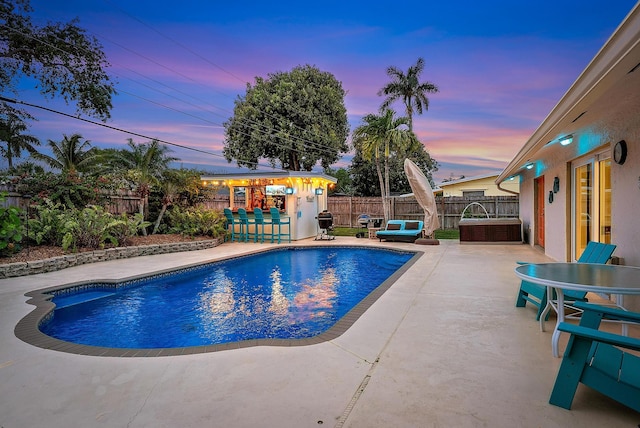 view of swimming pool with outdoor dry bar, a patio area, a fenced backyard, and a fenced in pool