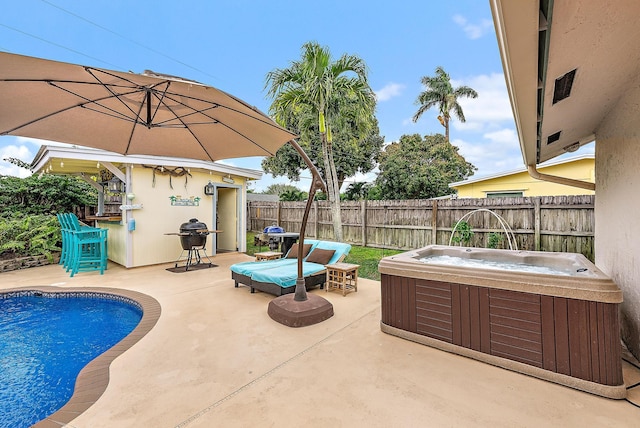 view of swimming pool with outdoor dry bar, a patio area, a fenced backyard, and a hot tub