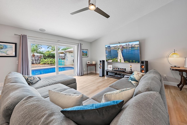 living room featuring a textured ceiling, baseboards, vaulted ceiling, and wood finished floors