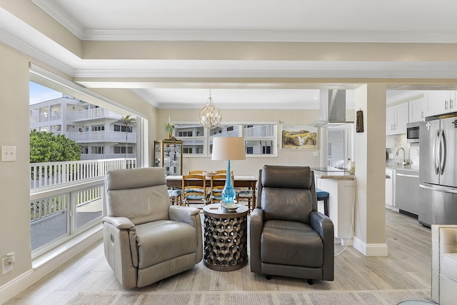 sitting room featuring ornamental molding, light wood-style floors, baseboards, and an inviting chandelier