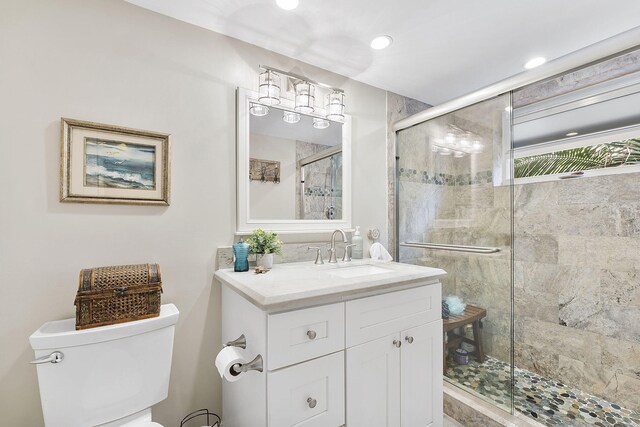 bathroom featuring toilet, a shower stall, recessed lighting, and vanity