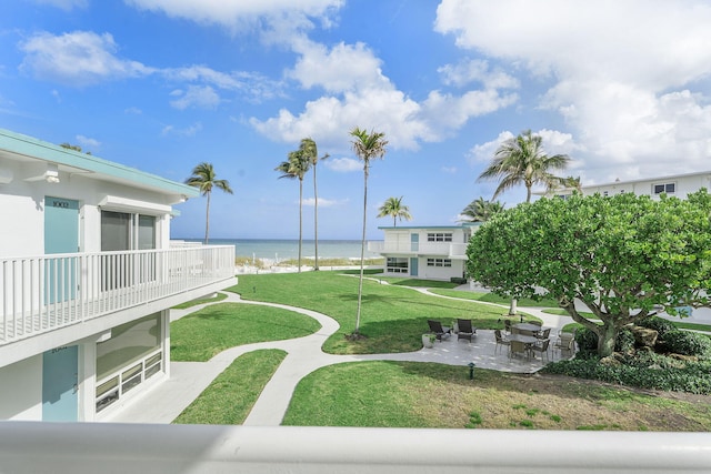 view of property's community with a patio area, a yard, and a water view