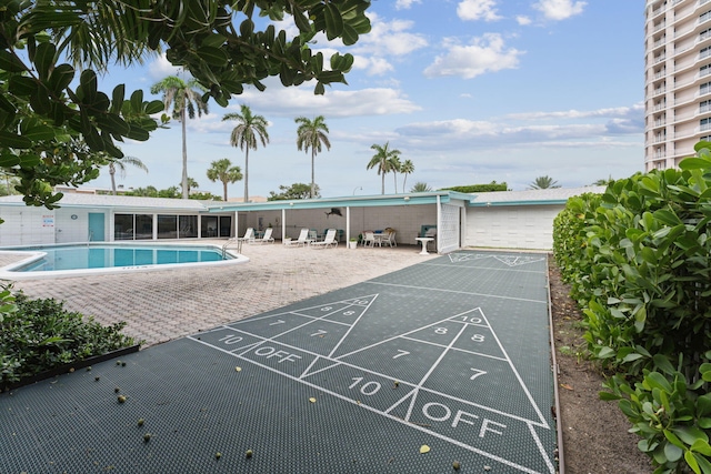 view of property's community featuring shuffleboard, a swimming pool, and a patio area