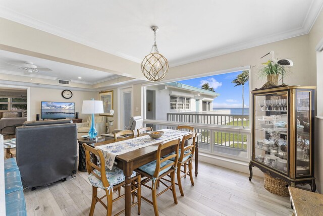 dining space featuring ornamental molding, light wood finished floors, ceiling fan with notable chandelier, and visible vents