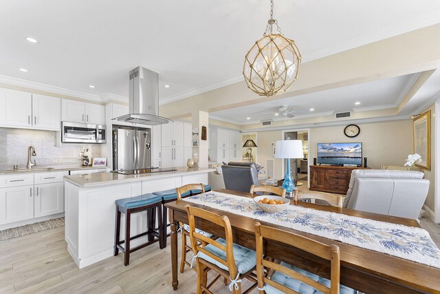 dining room with light wood finished floors, visible vents, a ceiling fan, ornamental molding, and recessed lighting