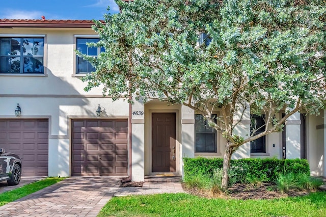 townhome / multi-family property featuring an attached garage, decorative driveway, and stucco siding