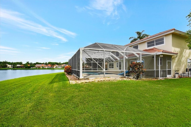 rear view of property featuring a water view, a lanai, a lawn, and a tiled roof