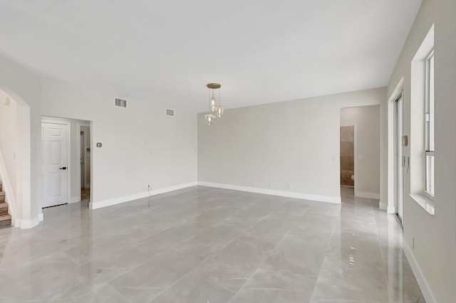 spare room with baseboards, visible vents, arched walkways, stairway, and a notable chandelier