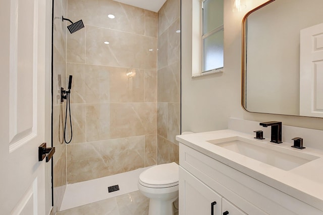 full bath featuring vanity, a tile shower, and toilet