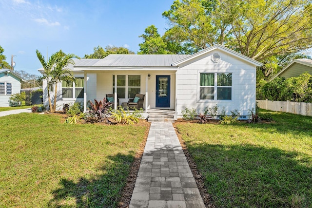 view of front of home featuring a porch, metal roof, fence, and a front lawn