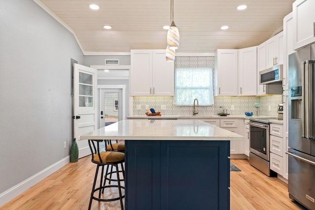 kitchen featuring a kitchen island, appliances with stainless steel finishes, a sink, a kitchen bar, and backsplash