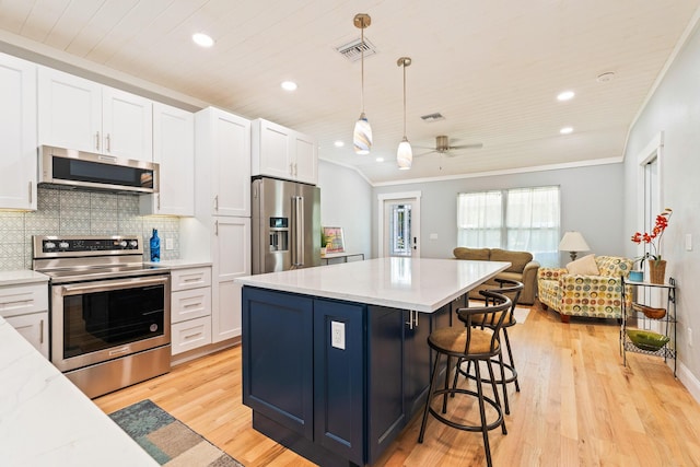 kitchen featuring appliances with stainless steel finishes, open floor plan, white cabinetry, and crown molding