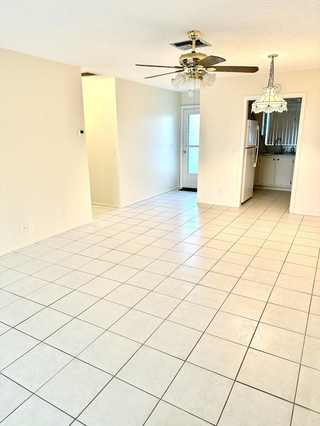 empty room featuring a ceiling fan, a textured ceiling, and light tile patterned floors