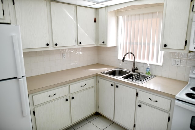 kitchen with light tile patterned floors, light countertops, backsplash, a sink, and white appliances