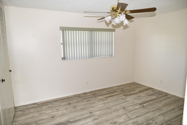 spare room featuring a textured ceiling, ceiling fan, wood finished floors, and baseboards