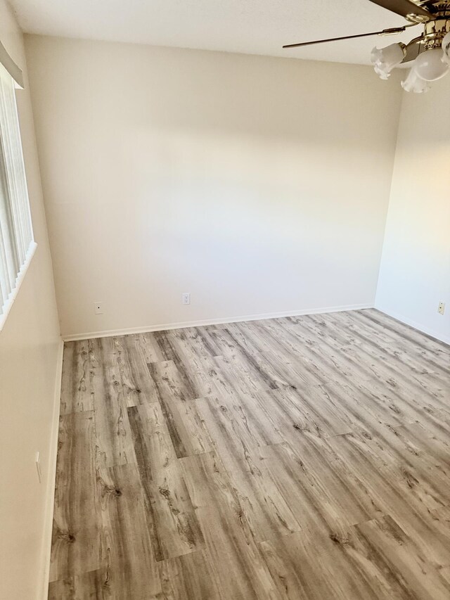 empty room with ceiling fan, wood finished floors, and baseboards