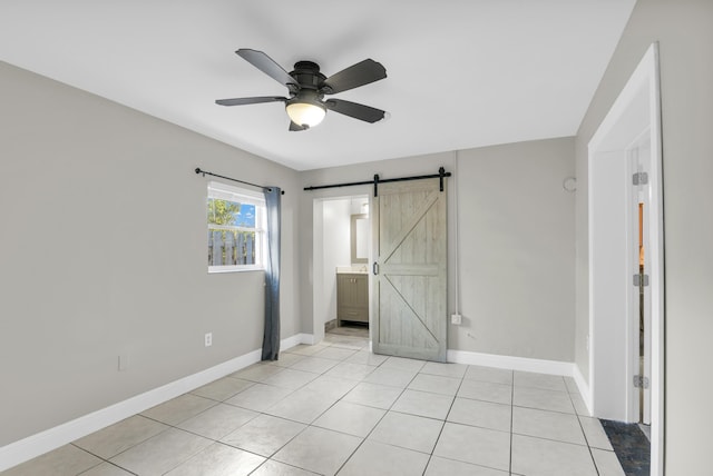 unfurnished bedroom featuring a barn door, baseboards, and light tile patterned flooring