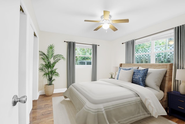 bedroom featuring a closet, wood finished floors, a ceiling fan, and baseboards