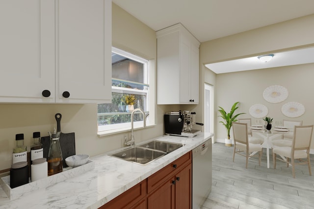 kitchen with light stone counters, a sink, white cabinetry, light wood-style floors, and dishwasher