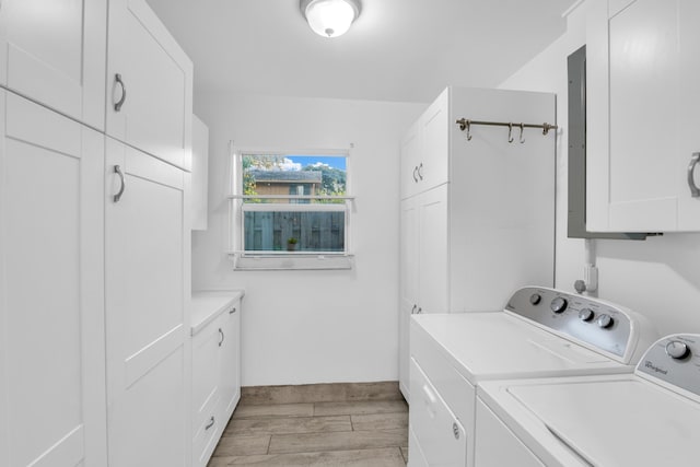 washroom featuring light wood-type flooring, washing machine and dryer, and cabinet space