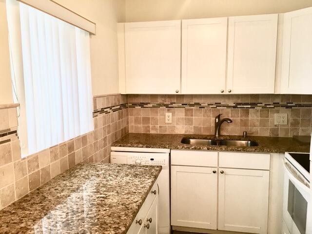 kitchen featuring dark stone counters, a sink, white cabinetry, and decorative backsplash