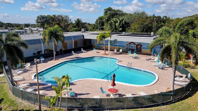 community pool with a patio area and fence