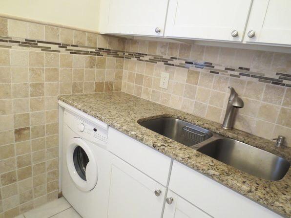 laundry area with tile walls, light tile patterned floors, washer / clothes dryer, cabinet space, and a sink