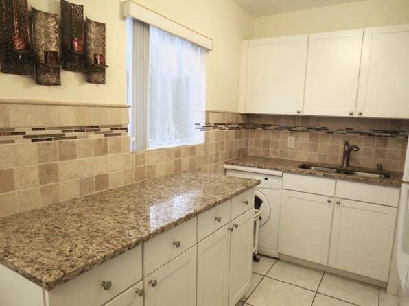 kitchen featuring light tile patterned floors, white cabinetry, a sink, and light stone countertops