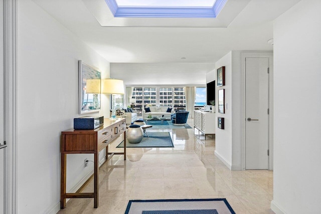 hallway featuring baseboards and a tray ceiling