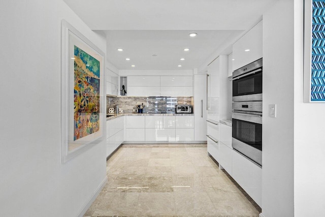 kitchen featuring stainless steel double oven, a toaster, white cabinets, tasteful backsplash, and modern cabinets