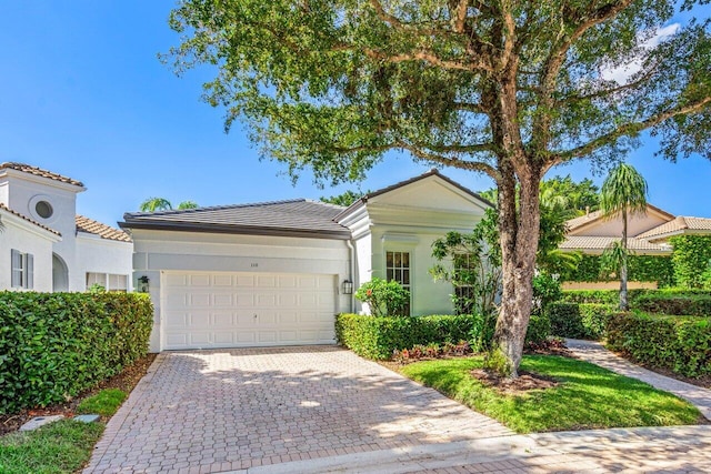 view of front of property with a tile roof, decorative driveway, a garage, and stucco siding