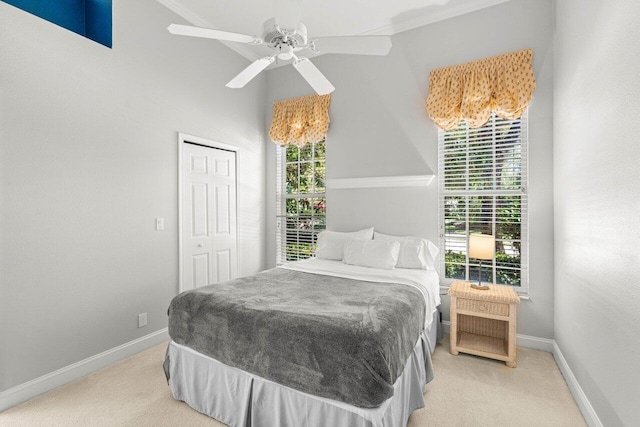 bedroom featuring light carpet, ceiling fan, a closet, and baseboards