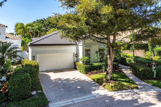 view of front of home featuring a tiled roof, decorative driveway, and a garage