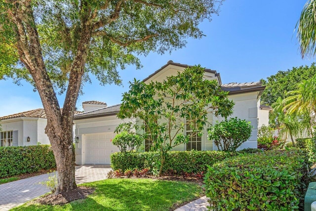 view of front of home featuring a tiled roof, a garage, decorative driveway, and stucco siding