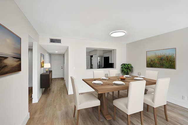 dining area featuring light wood-style floors, baseboards, and visible vents