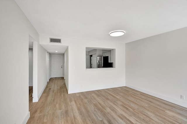 unfurnished room featuring light wood-style flooring, visible vents, and baseboards