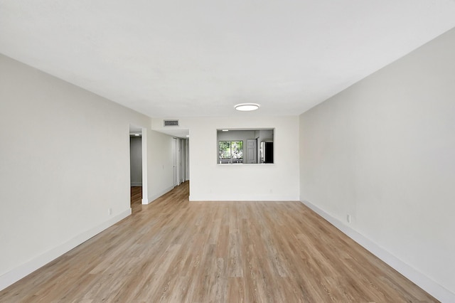 empty room featuring light wood-type flooring, baseboards, and visible vents