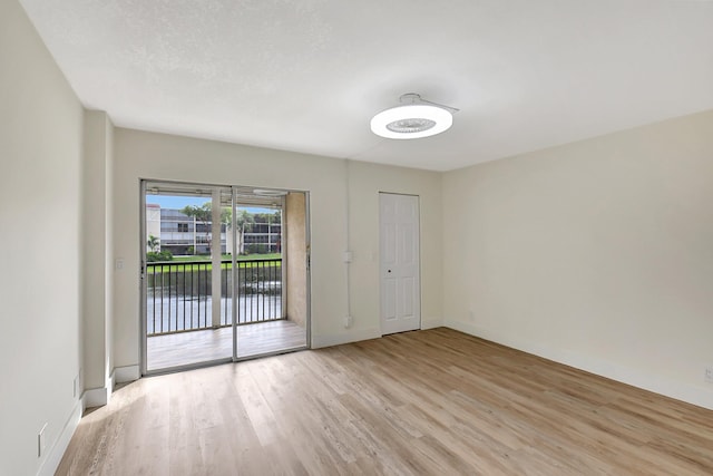 spare room with light wood-style floors, a textured ceiling, and baseboards