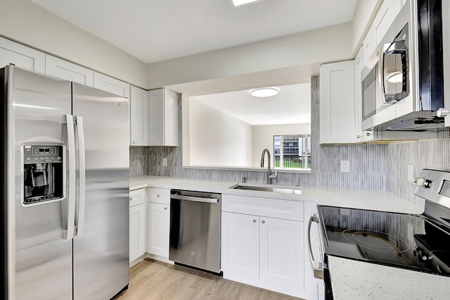 kitchen with stainless steel appliances, light countertops, decorative backsplash, white cabinets, and a sink