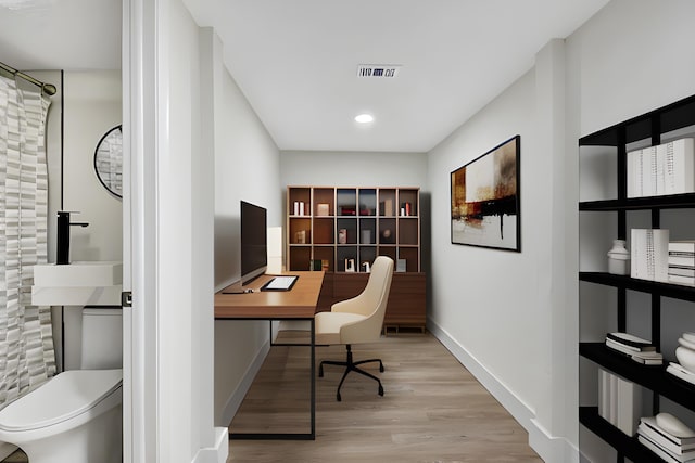 office area featuring visible vents, baseboards, and wood finished floors